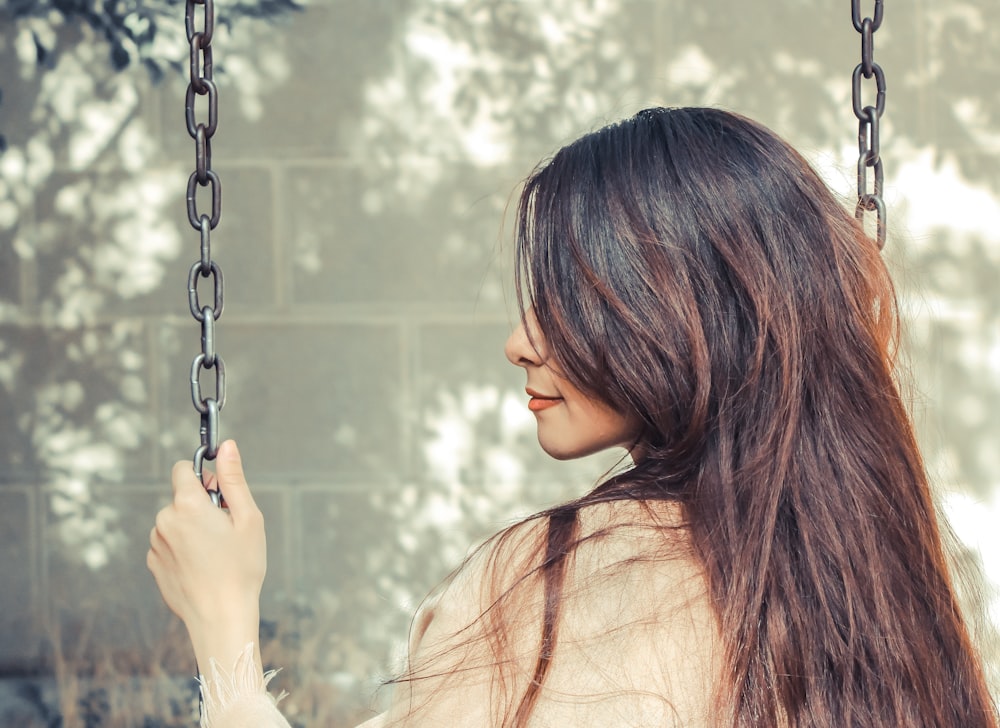 woman seats on swing during daytime