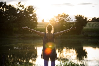 woman standing beside lake under white sky