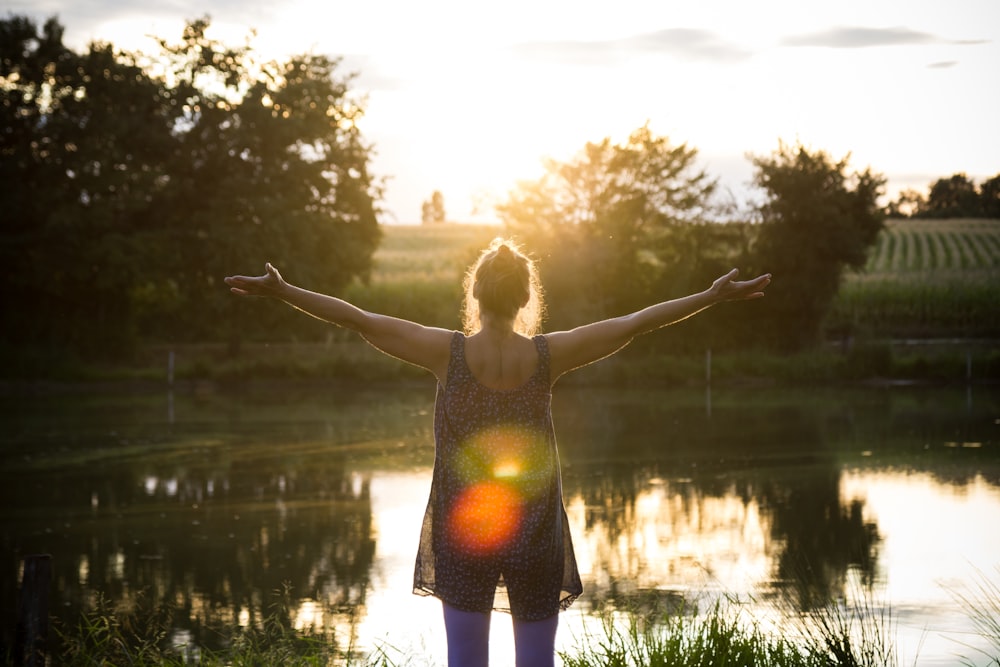 woman standing beside lake under white sky