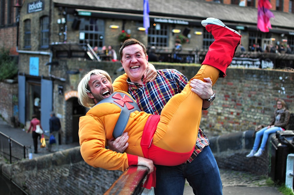 man standing on gray bridge while carrying a man during daytime