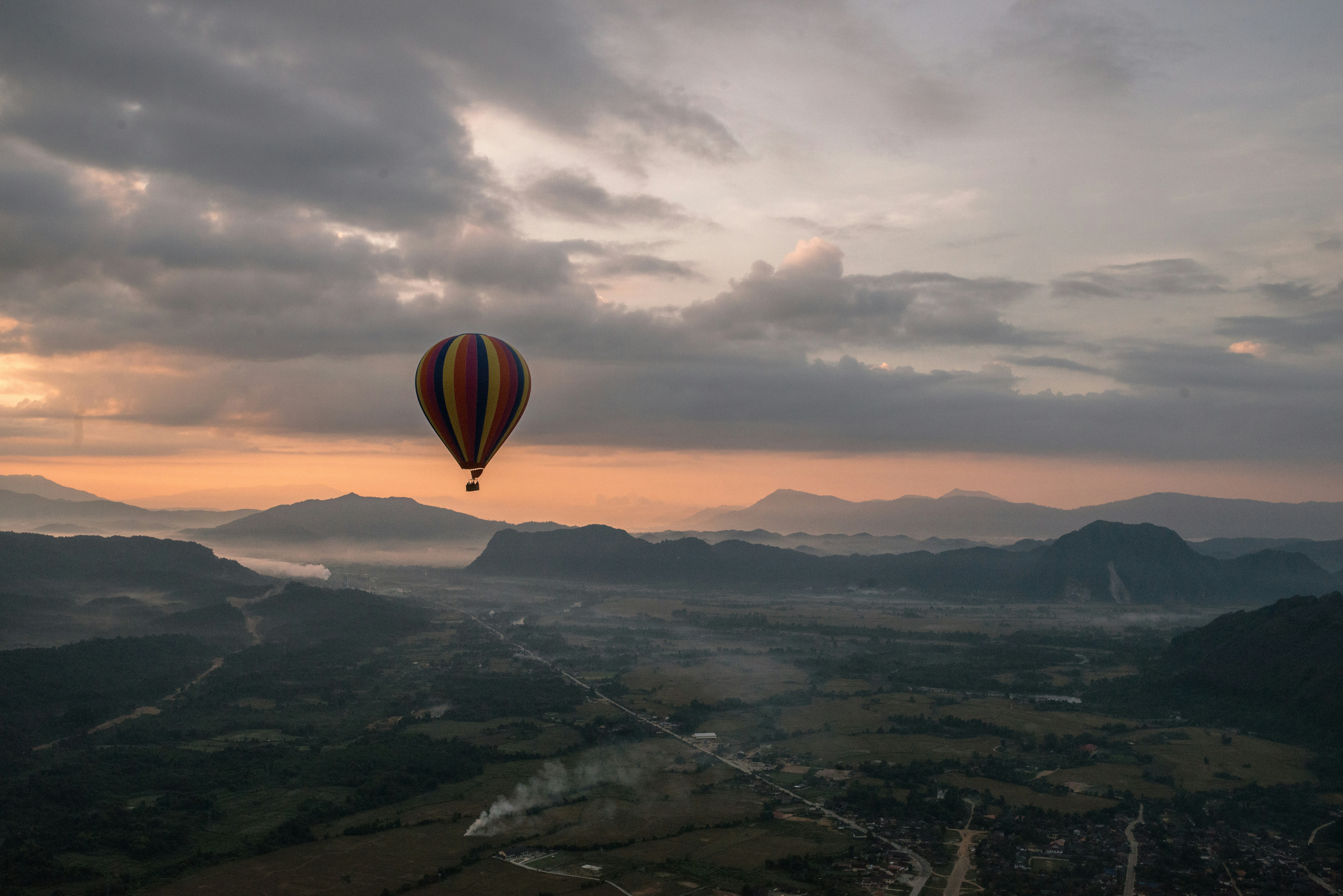 hot air balloon floating above green mountains during day