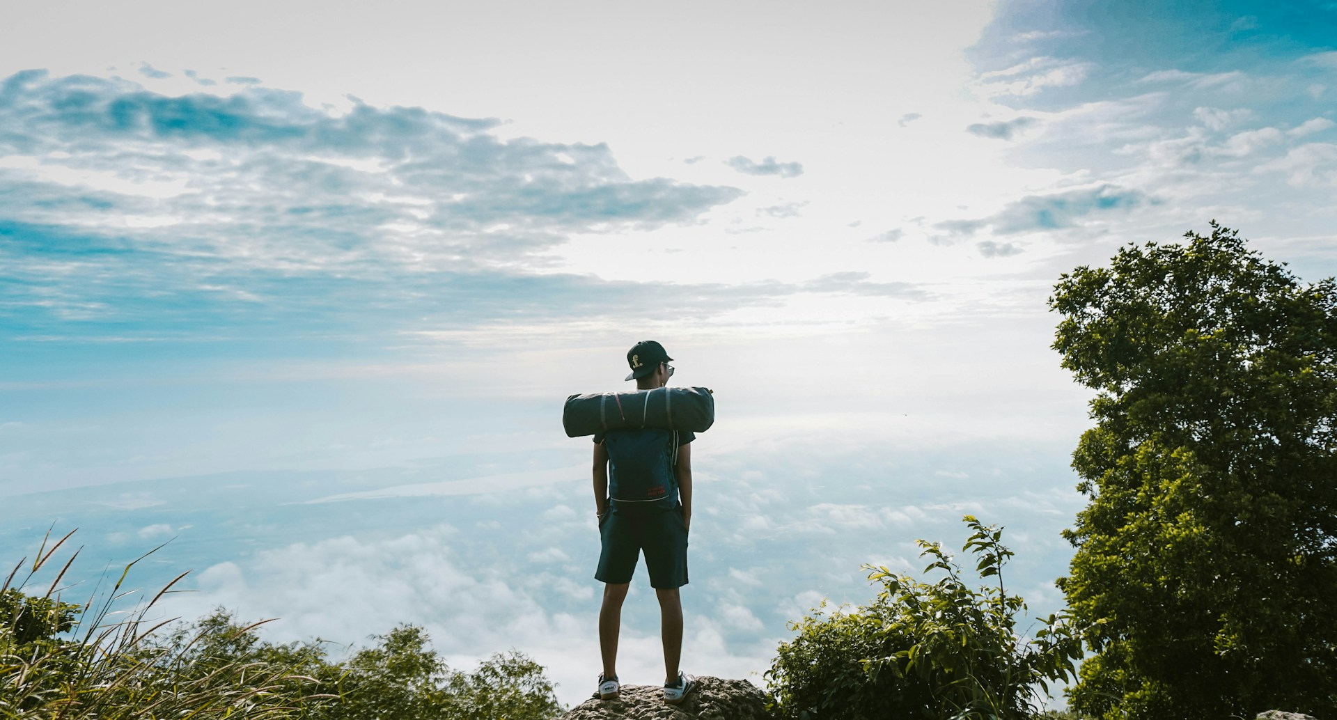 man in black shirt standing on cliff facing sea of clouds