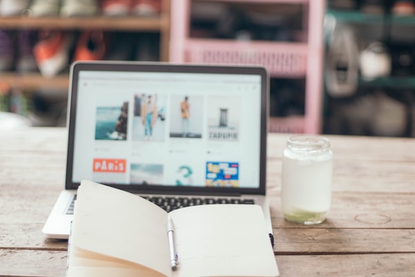 Laptop met dagboek en glazen pot op een bureau