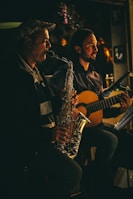 Johnny Mag Sax performing alongside a vocalist and guitarist at an intimate party.