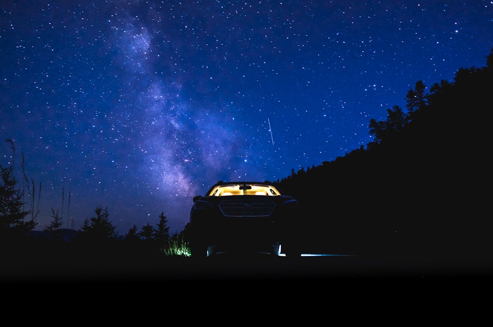 car parked in forest under starry sky