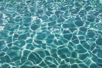 Sunlight filtering through water, creating dancing patterns on the pool floor with blue and beige hues