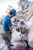 man sitting on rock fixing safety harness