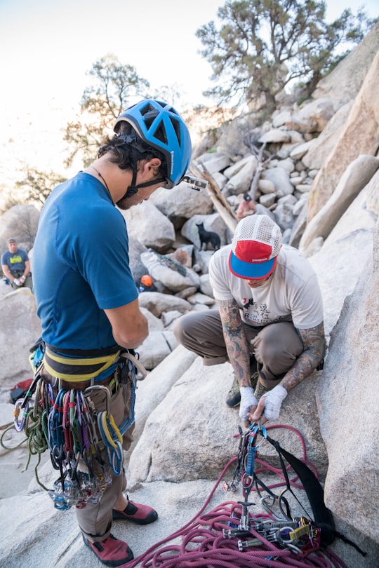 man sitting on rock fixing safety harness in Joshua Tree National Park Visitor Center United States