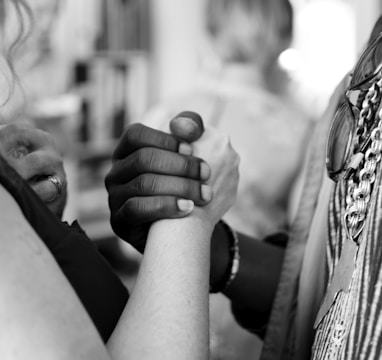 grayscale photo of man and woman holding their hands