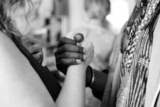 grayscale photo of man and woman holding their hands