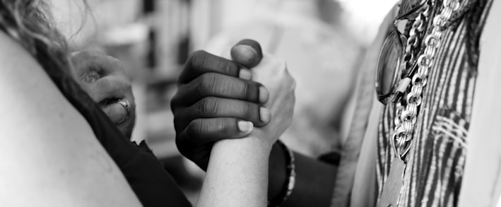 grayscale photo of man and woman holding their hands