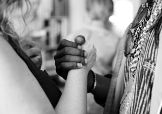 grayscale photo of man and woman holding their hands