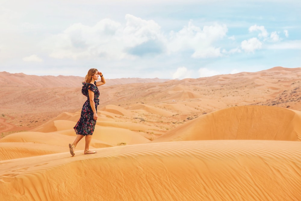 woman walking on sand dunes during daytime