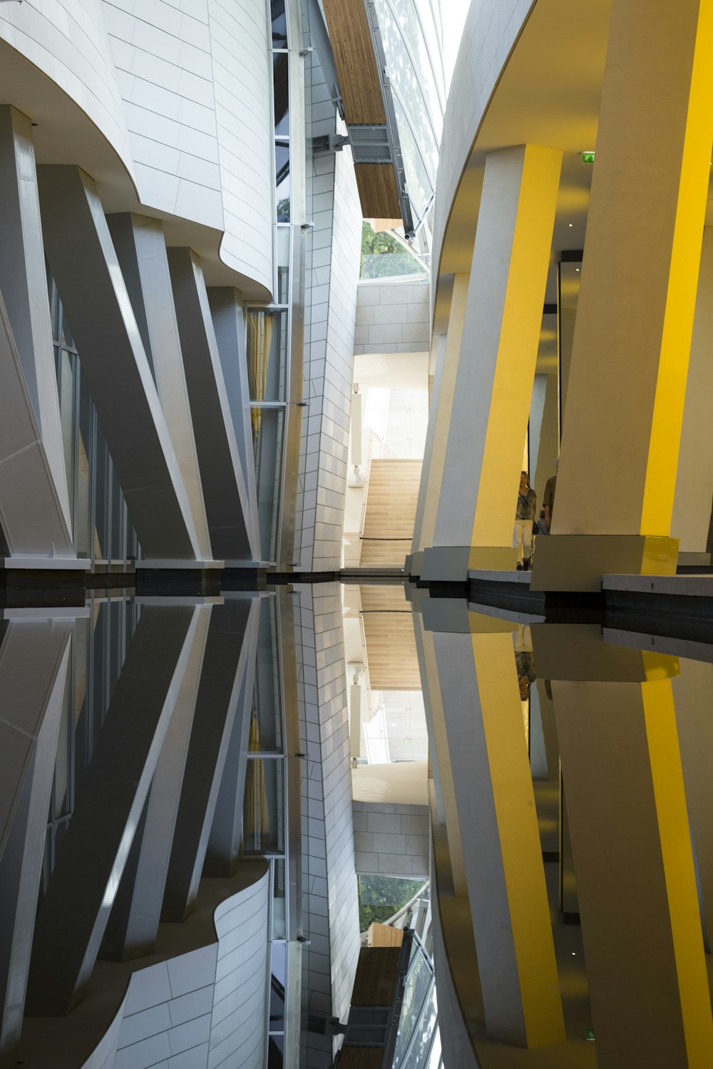 Réflexion d’un bâtiment jaune et blanc sur l’eau pendant la journée