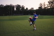 man juggling ball on grass field