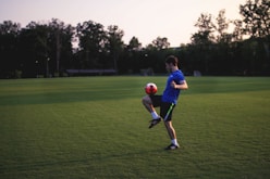 man juggling ball on grass field