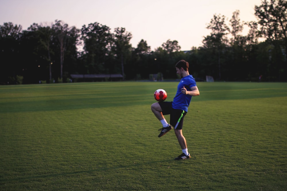 man juggling ball on grass field