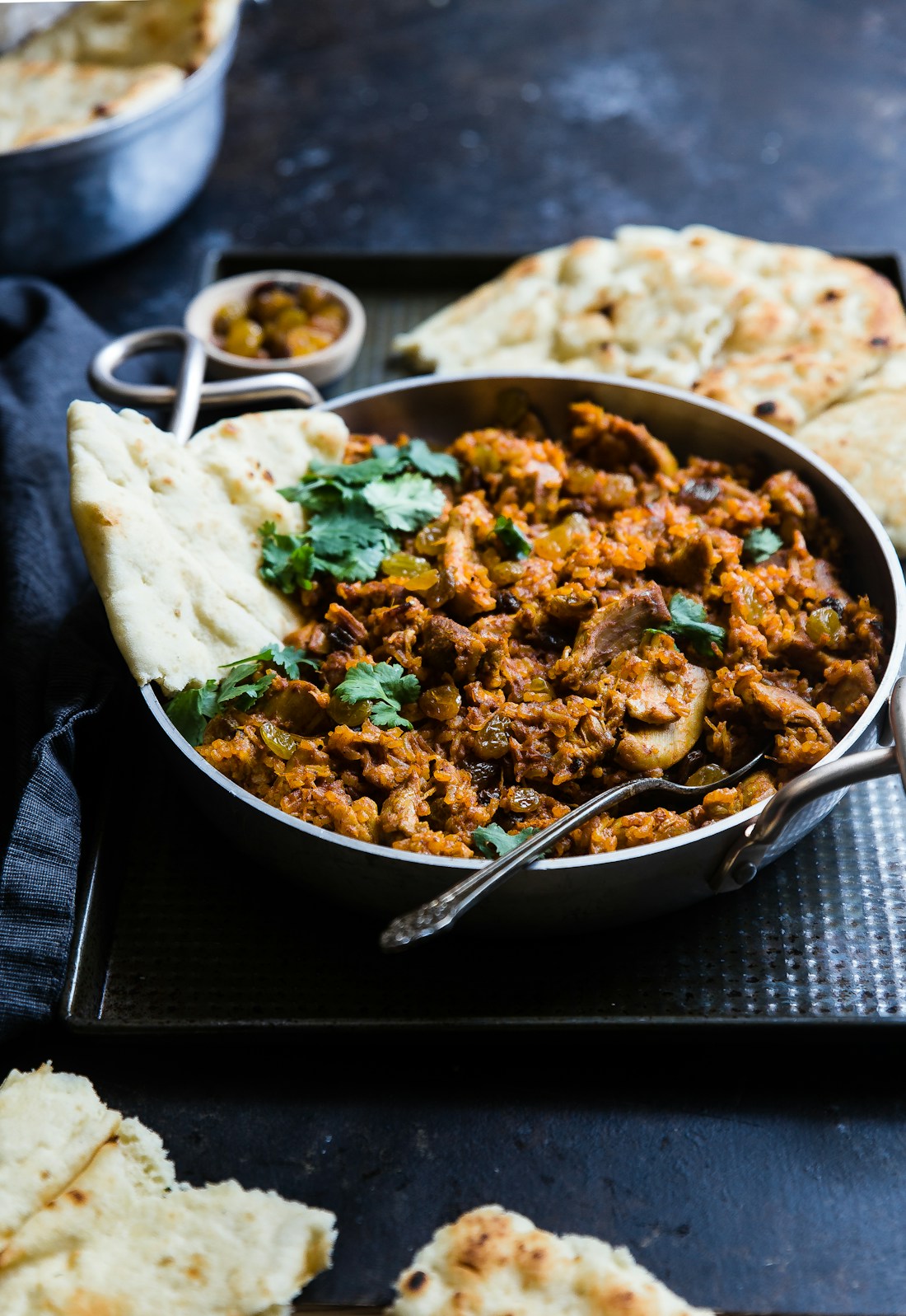Slow-stewed Jamaican curry in cast iron, photographed in low light.