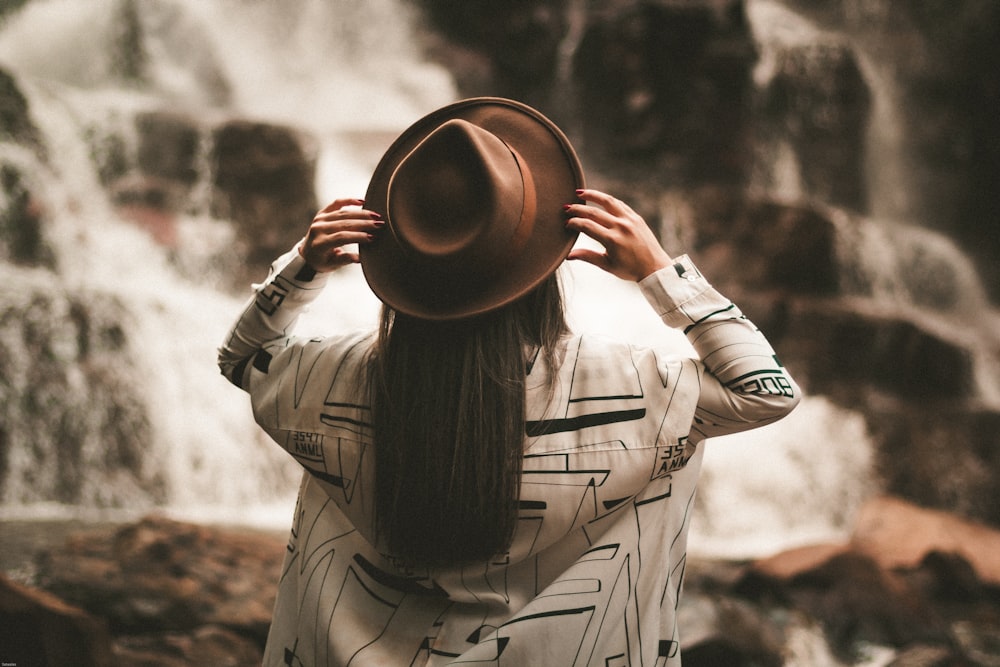 selective focus photography of woman holding brown fedora hat at daytime