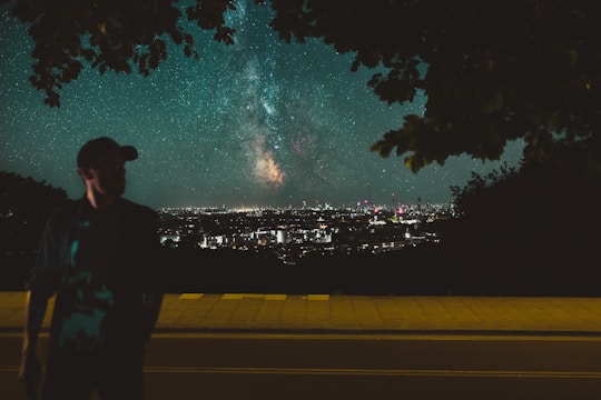 A nighttime city skyline merging seamlessly with a vibrant star-filled galaxy above.