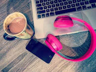 A stylish tablet resting on a wooden desk next to headphones and a coffee cup.