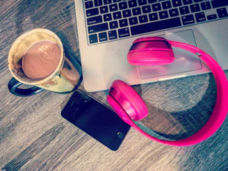 A stylish tablet resting on a wooden desk next to headphones and a coffee cup.