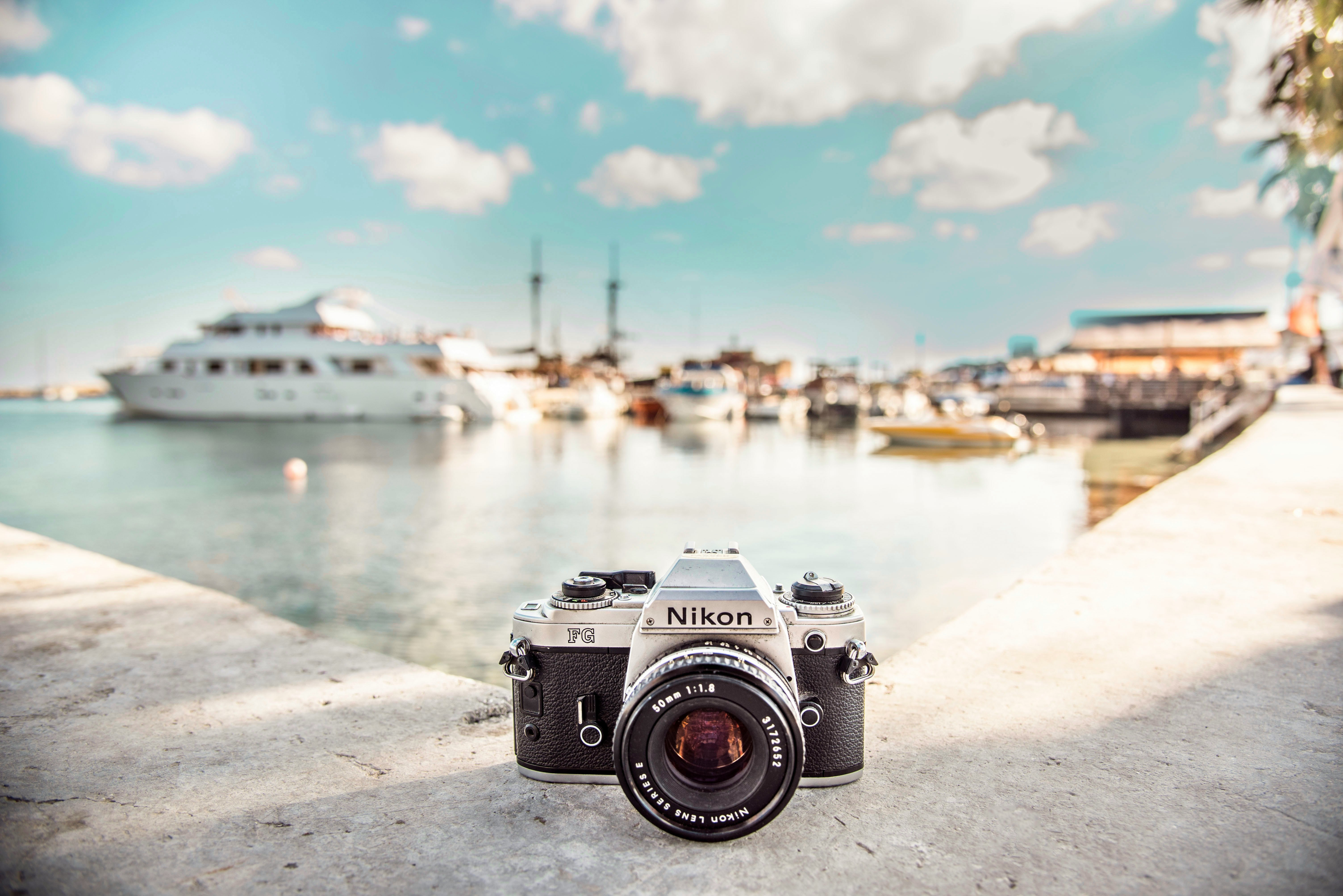black and silver Nikon camera near boats during daytime