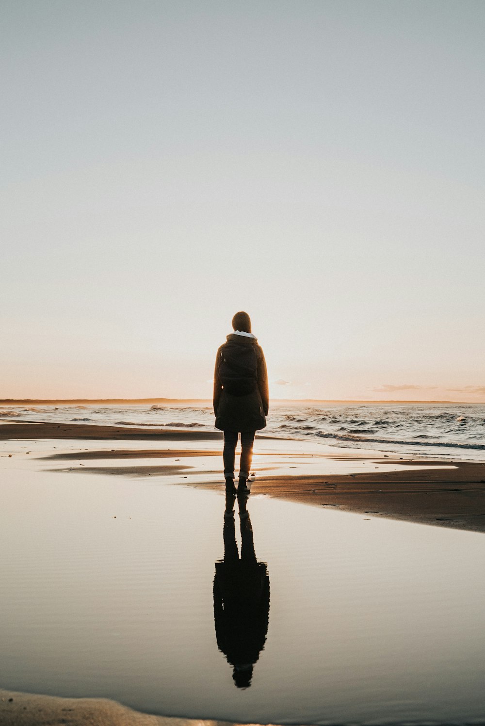 femme debout sur le sable près du rivage