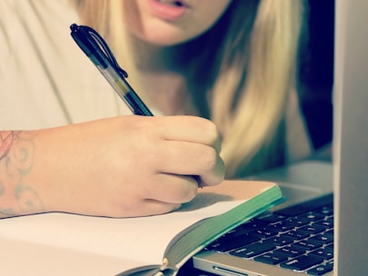 A focused individual writing in a notebook during a coaching session.
