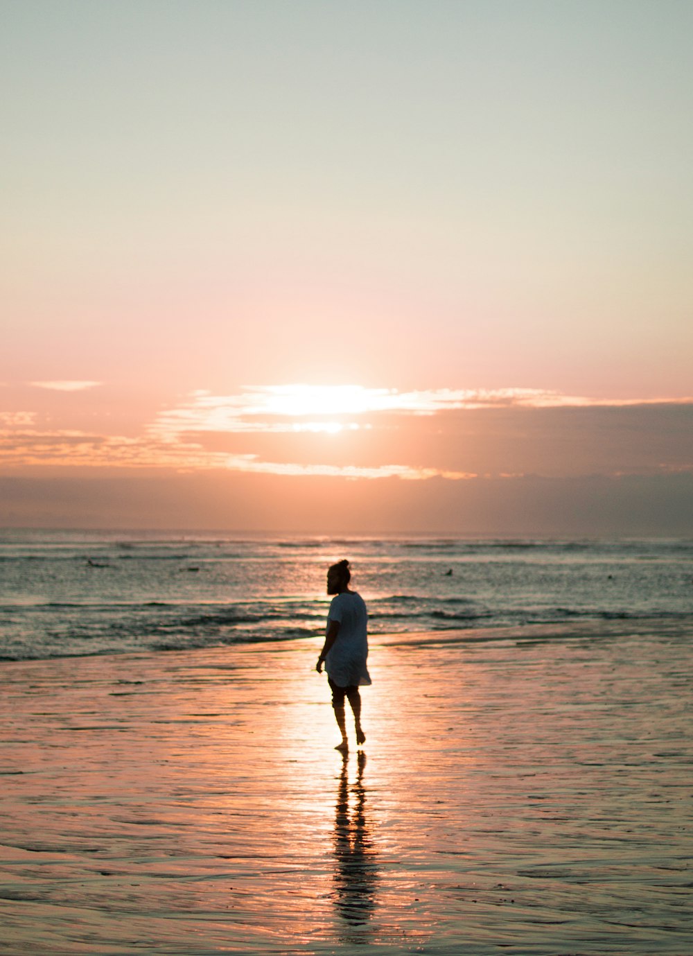 person walking on seashore during golden hour