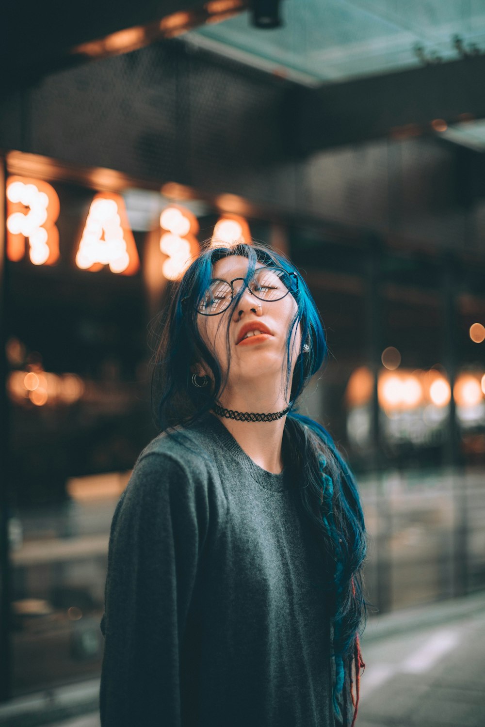 woman wearing black crew-neck long-sleeved shirt standing near neon light signage