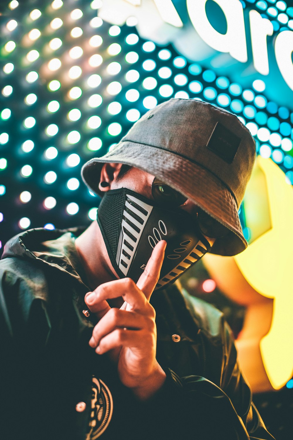 homem usando bucket hat preto, máscara e jaqueta durante a noite