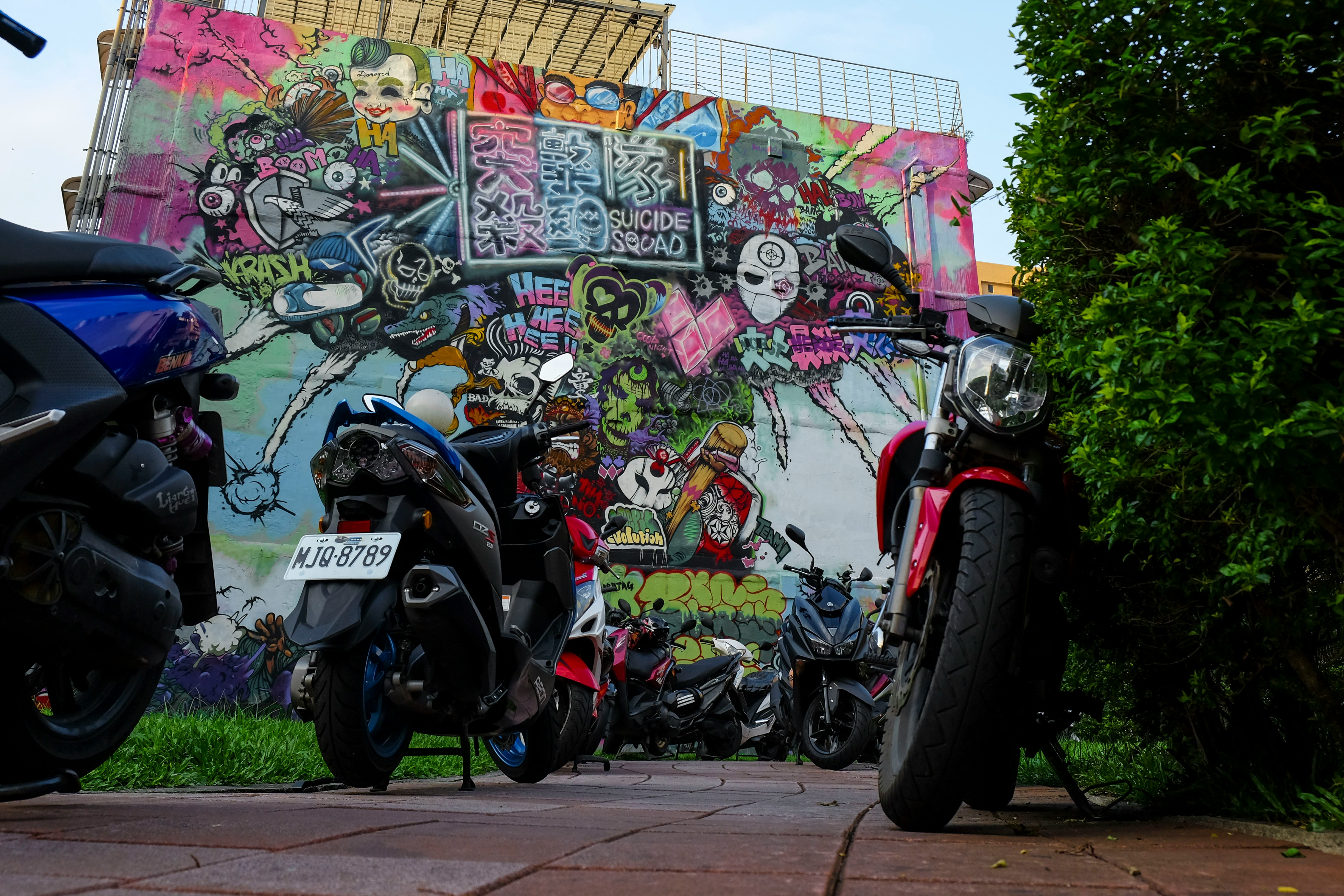 assorted-color motorcycles parking near wall wit graffiti art