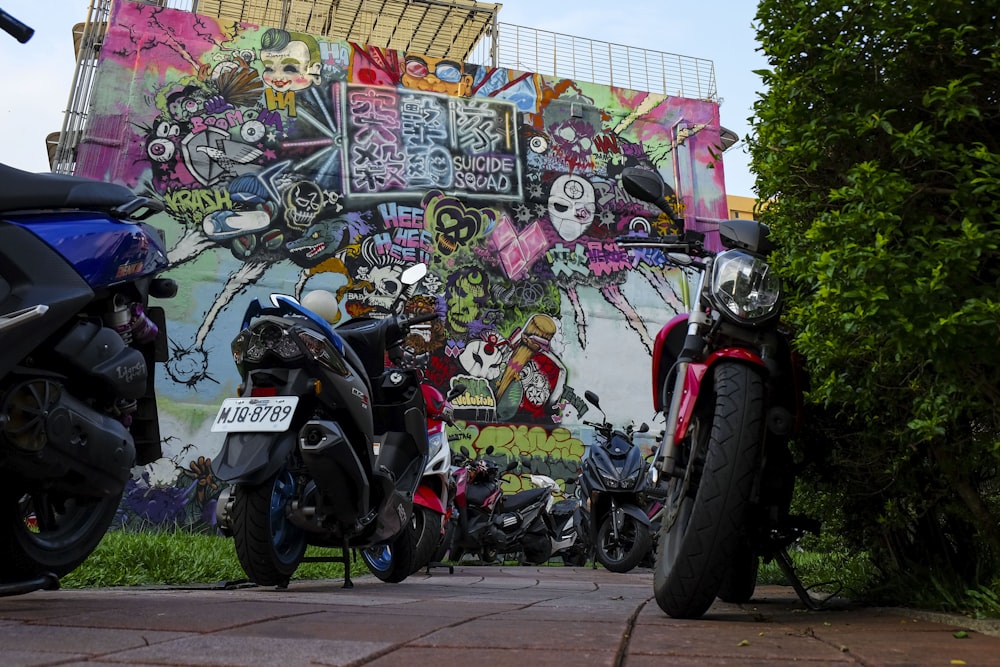 Parcheggio moto di colori assortiti vicino al muro con graffiti art