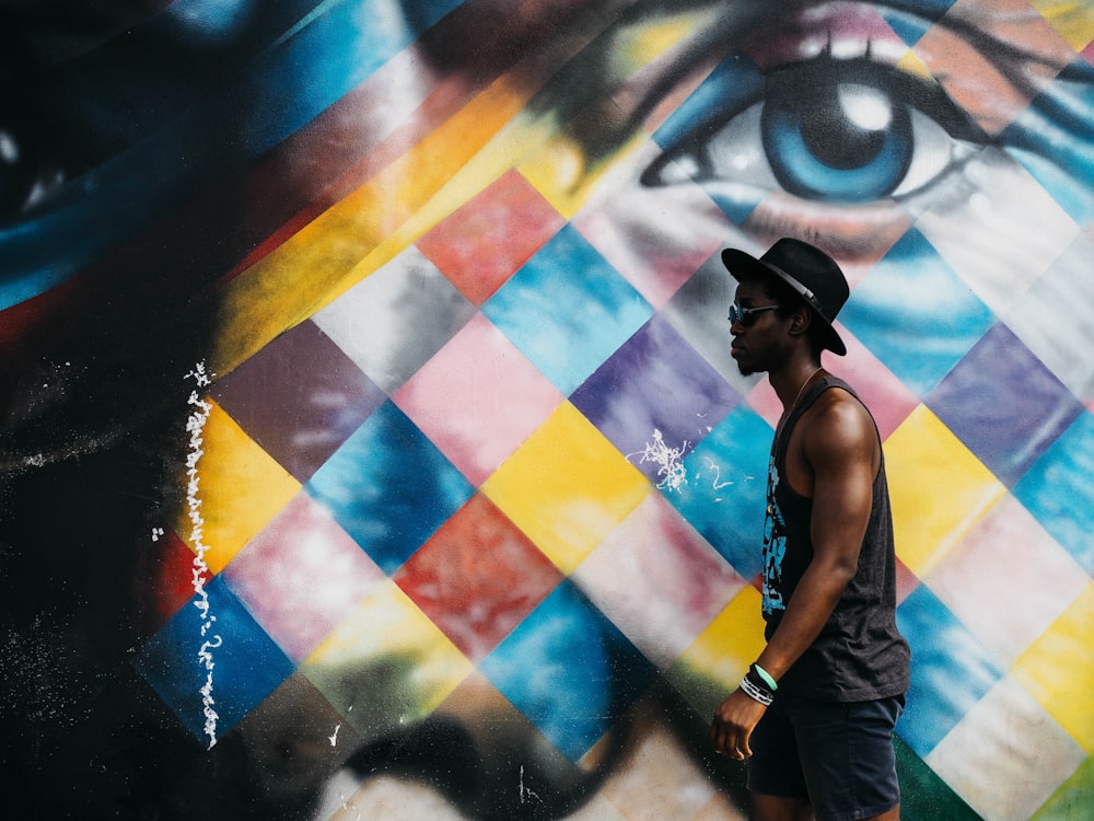 man in black tank top wearing black bucket hat beside wall art