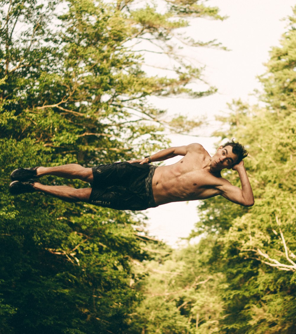 man on mid air near trees at daytime