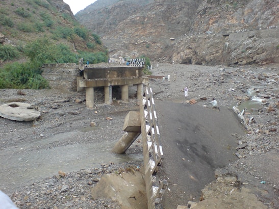 Community members gathered near a damaged road section discussing repairs.