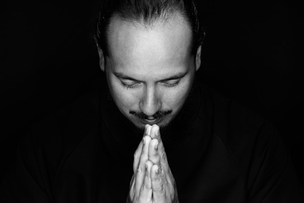 Foto en escala de grises de un hombre rezando