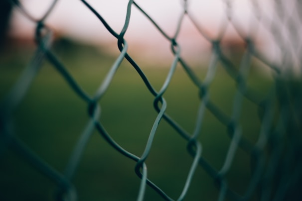 Close-up of thick aluminum fence clips securing a wire fence on a sunny farm.