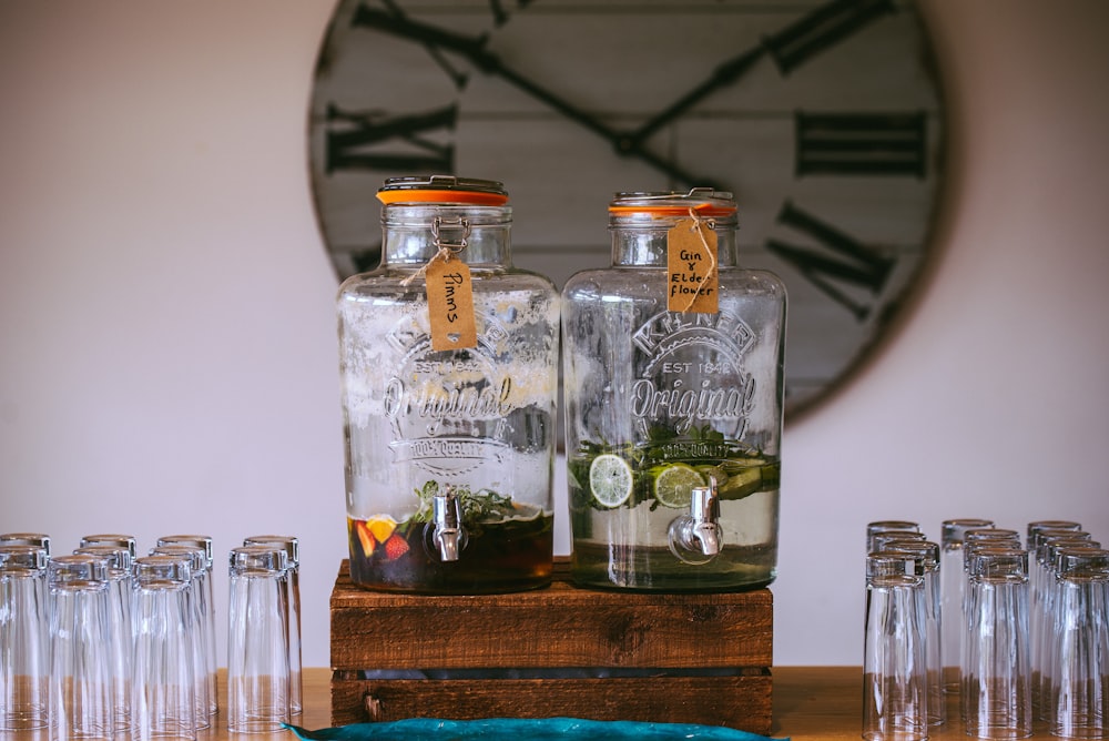 two glass beverage dispensers filled with sliced fruits on top of brown wooden rack