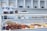 A display counter filled with a variety of pastries and baked goods, including tarts and other desserts. The upper shelves have packaged treats tied with ribbons, and the background shows a neatly organized, modern bakery setting.