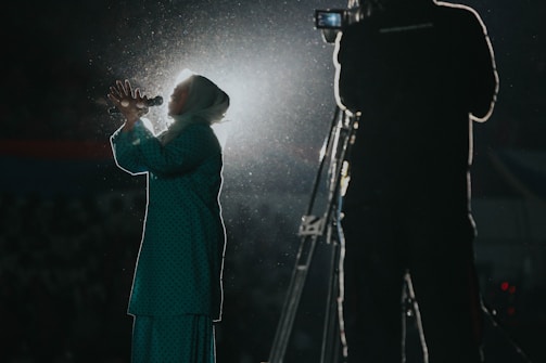 An African woman journalist reporting passionately with a microphone, city skyline behind her.