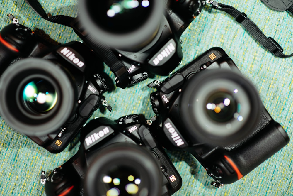 four black Nikon DSLR cameras on green textile
