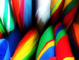 Colorful array of folded umbrellas neatly arranged on a wooden table.