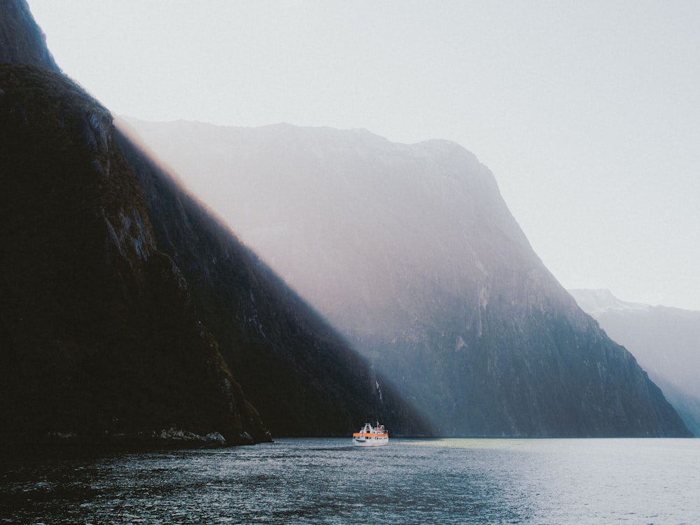 white boat sailing near montain