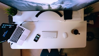 turned on laptop near smartphone and Apple keyboard and Magic Mouse on white computer desk