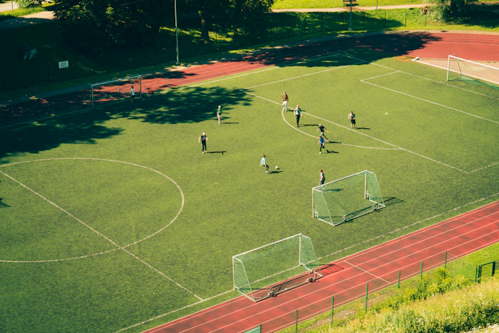 Students playing football on campus outdoor sports field