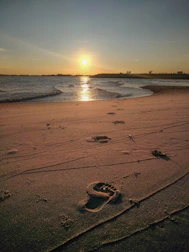 A serene beach at sunset with footprints leading to the water.