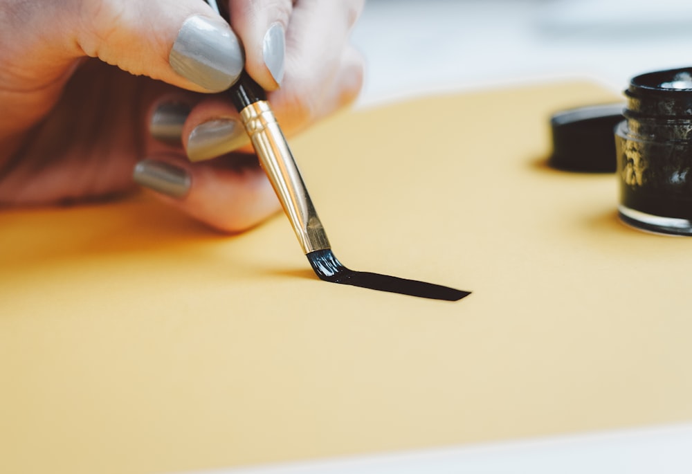 Persona escribiendo en papel beige con tinta negra
