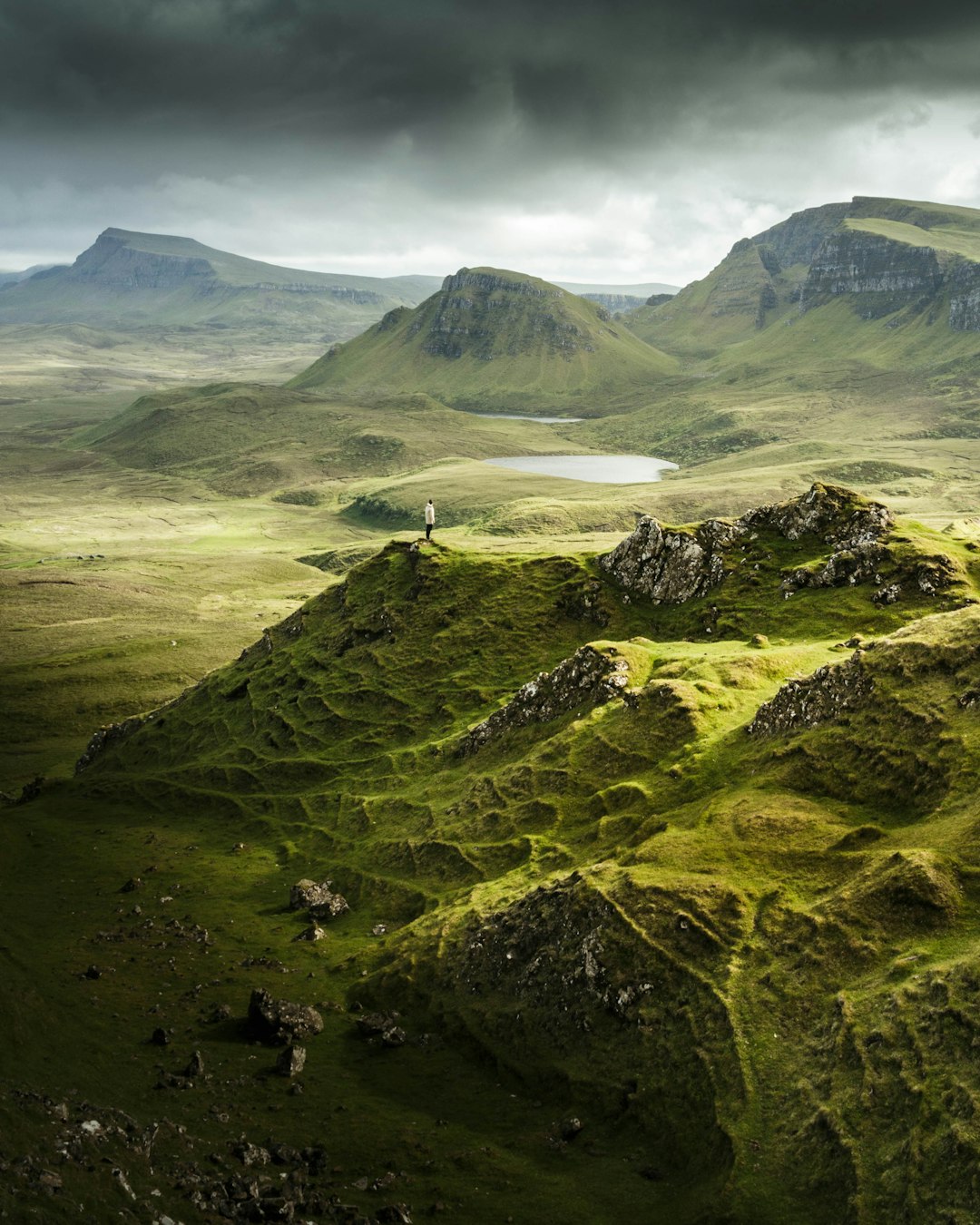 aerial view photography of person standing on mountain under cloudy sky